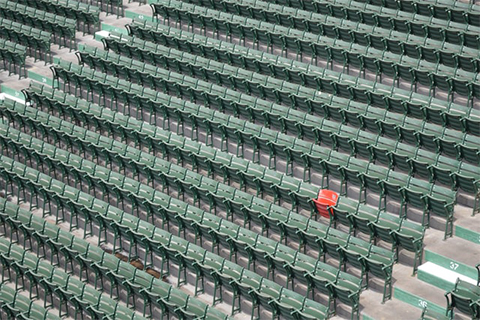 stadium of green chairs with one red chair